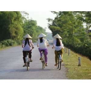 com Three Girls in Conical Hats Cycling on Rural Road North of Hanoi 